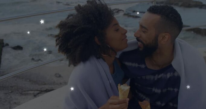 Animation of glowing star icons over african american couple embracing each other at the beach