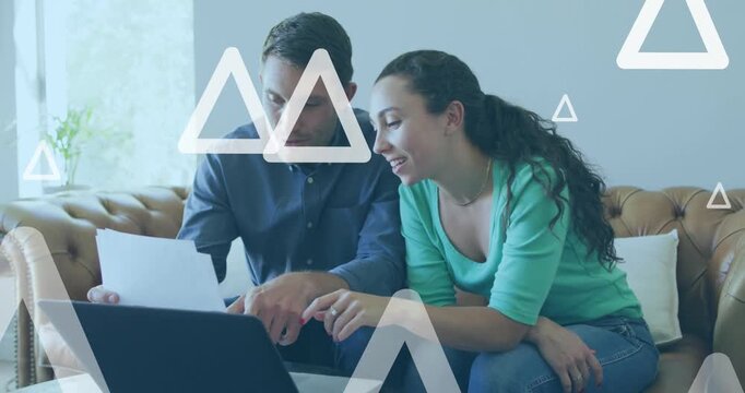 Animation of white triangles over caucasian couple using laptop