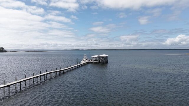 Long wooden pier with boats stretching into calm coastal Grand Lagoon water, 30A, Florida, USA