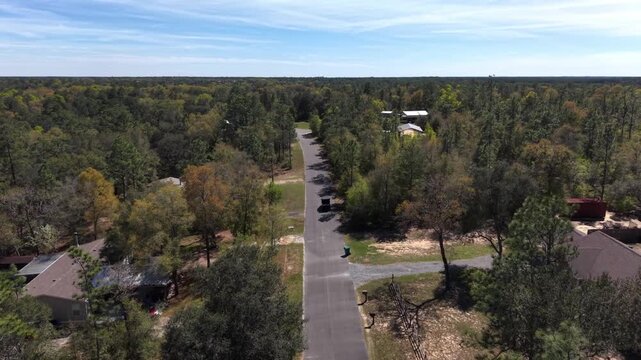 Straight rural road cutting through dense forest landscape during following a car from above in 30A area, Florida, USA