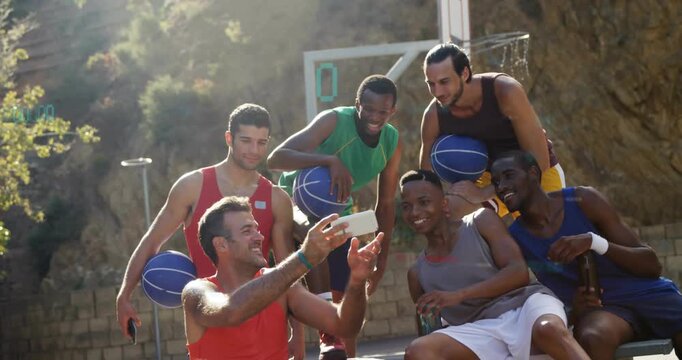 Six teammates gathering on outdoor sports court pulling smartphone and framing shot for team memory