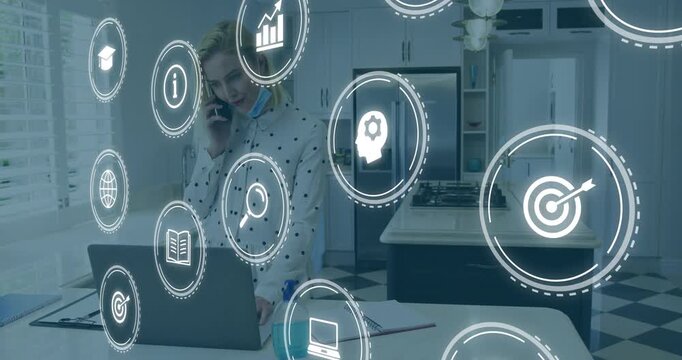 Woman holding phone, typing on laptop in kitchen receiving business call, icons drifting into frame