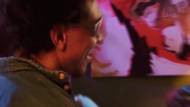 Handycam shot of upbeat young adults moving on dance floor raising beer bottles and cocktail glasses in toast at home party