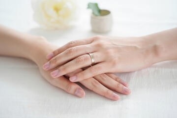 Naklejka premium Elegant Display of Intertwined Hands Showcasing a Ring Against a Soft Floral Background, Symbolizing Love and Connection