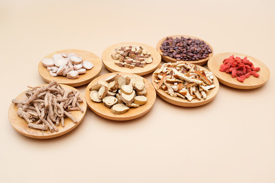 Eight types of traditional Chinese medicinal herbs displayed separately on wooden plates