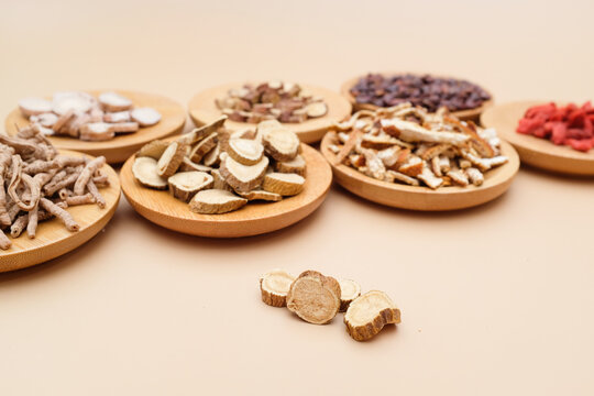 Various traditional Chinese medicinal herbs sliced and arranged on wooden plates for display