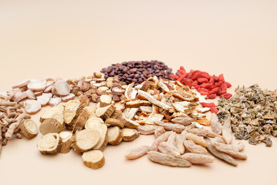 A variety of traditional Chinese medicinal herbs including sliced roots, dried fruits, and botanical ingredients arranged on a neutral background
