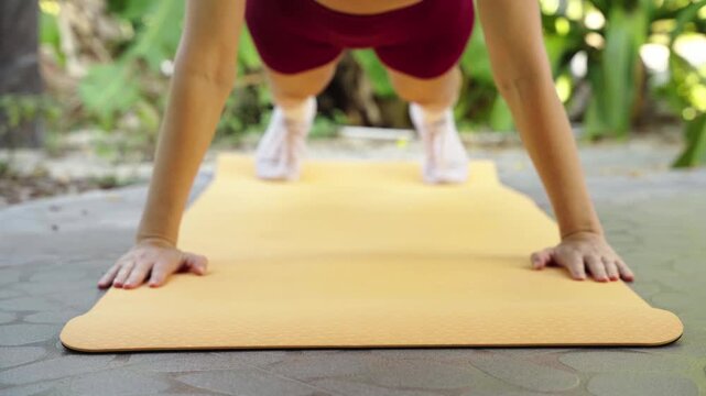 Woman doing push-ups on yoga mat outdoors