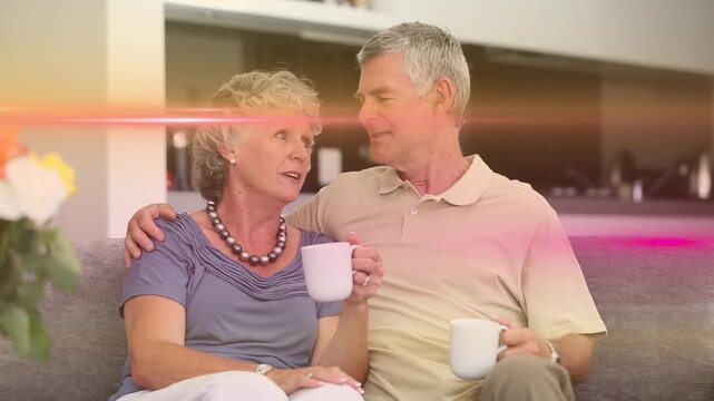 Animation of light trails over senior caucasian couple holding mugs and drinking