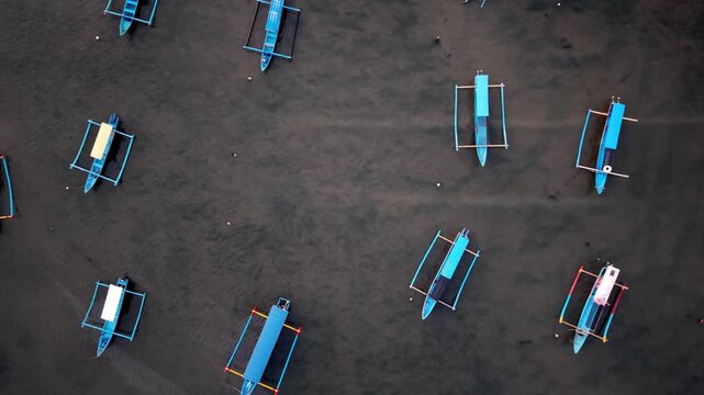 Aerial Top Down View of Colorful Traditional Balinese Jukung Boats Floating on Calm Sea at Pantai Sidakarya
