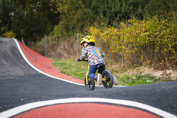 Obraz premium A young boy riding a bike on a paved bike track with a red and white design