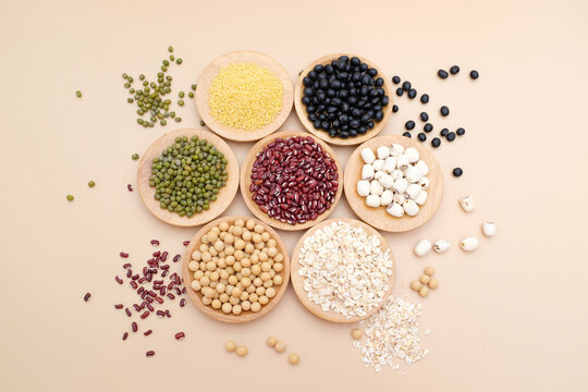 Top view close-up of various whole grains and legumes arranged in wooden bowls on a neutral background