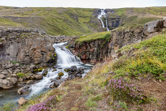 Waterfall winds through the valley across Eastern Iceland in the summer
