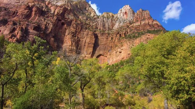 Scenic footage capturing the vibrant fall foliage and majestic sandstone cliffs viewed from the sandy path of the Sand Bench Horse Trail, a loop hike popular for horseback riding and hiking, located n