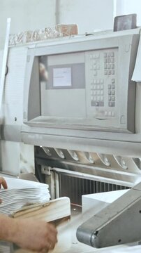 Man works with cutter guillotine machine at printing factory - typography