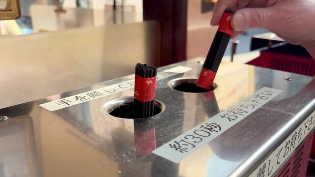 Lighting incense sticks at Kogan-ji Temple Togenuki Jizo Sugamo Tokyo Japan.