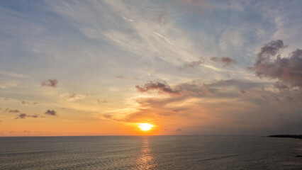 Obraz premium Scenic Golden Sunset Over the Calm Ocean with Dramatic Clouds and Horizon View