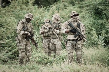 Tactical military unit in camouflage uniforms operating in dense vegetation © FotoArtist