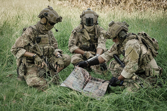 Military personnel studying a map in a grassy field during training exercises