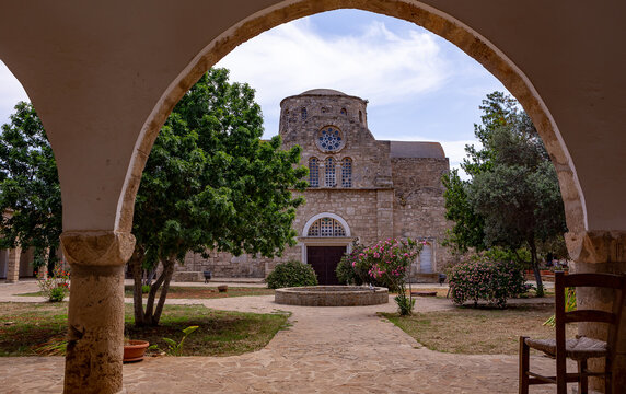 Historic exterior view of the Monastery of Saint Barnabas in Famagusta, Northern Cyprus, showcasing ancient stone architecture, a domed church, and dramatic sky.


