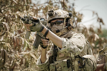 Fototapeta premium Soldier in tactical gear aims rifle with focus in outdoor environment