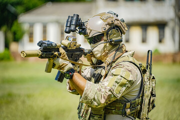 Special forces operator in camouflage gear aiming a rifle with night vision goggles © FotoArtist
