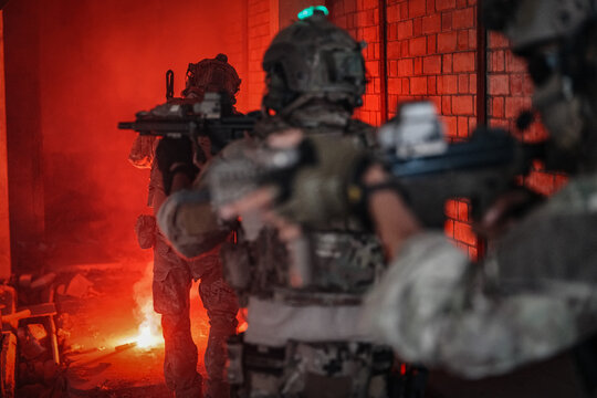 Special forces soldiers advance through smoke with tactical gear and weapons