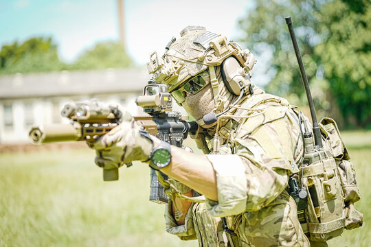 Soldier in tactical gear aiming an assault rifle with advanced optics and suppressor