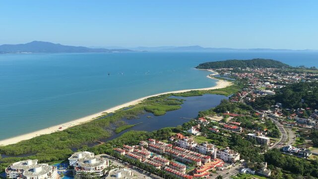 Vibrant aerial of Praia da Ponta das Canas featuring sandy beach, calm lagoon waters and lush forested headland.
