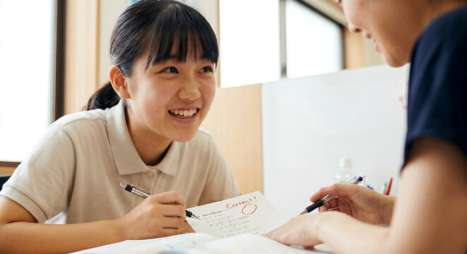 個別指導塾で講師と笑顔でコミュニケーションを取りながら楽しく勉強に励む中高生の女子生徒