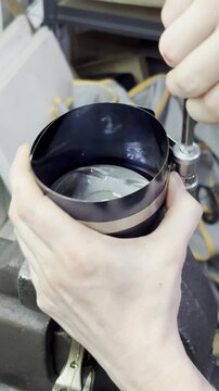 Hands tightening a piston ring compressor tool on car piston.