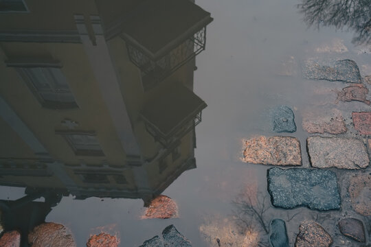 Reflection of a building with balconies in a puddle