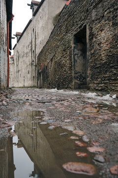 Reflection of medieval stone wall in street puddle