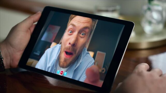 Joyful man speaking tablet online at restaurant closeup. Friends video calling