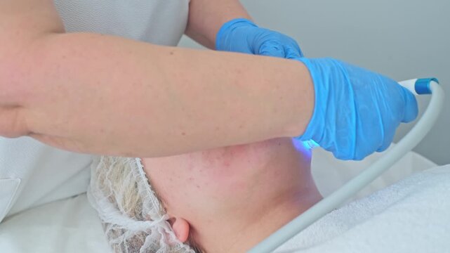 Cosmetologist performs an advanced hydro-peeling treatment using blue light for deep cleansing and rejuvenation on a client.
