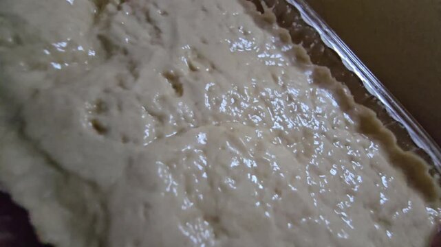 Sesame halva in a transparent plastic container. Close-up side view of traditional Mediterranean sweet in retail packaging on a wooden surface.