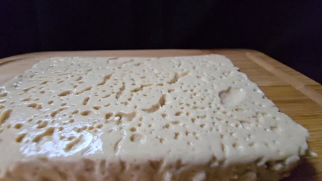 Extreme macro of sesame halva texture. Top view showing glossy, creamy surface and soft consistency of traditional Mediterranean sweet in a container.
