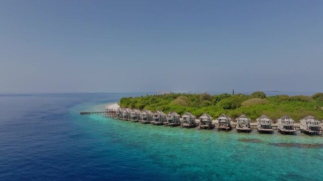 Aerial view of bungalows on an island with lush green vegetation contrasting against the turquoise sea, Hanimaadhoo, Thiladhunmathee Uthuruburi, Maldives.