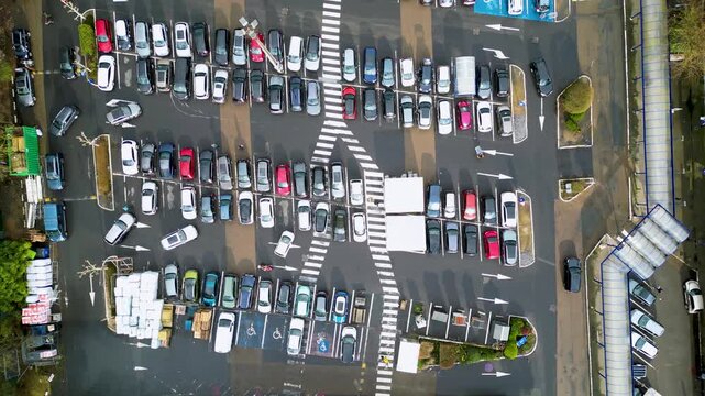 Aerial view of a densely packed car park with orderly rows of colorful cars, creating a vibrant mosaic of vehicles and marked parking spaces, Auderghem, Belgium.