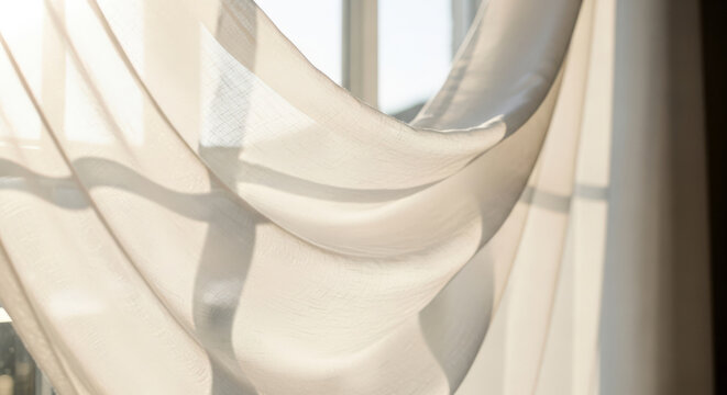 White linen curtain blowing in the breeze by window