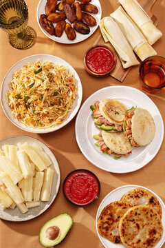 Flatlay of Latin American dishes: pupusas, arepas, curtido, tajadas, humitas, yuca