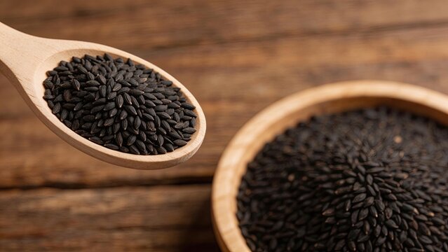 Black cumin seeds on wooden spoon and bowl healthy organic spice for cooking natural ingredient traditional herbal remedy closeup texture rustic wooden background nutrition