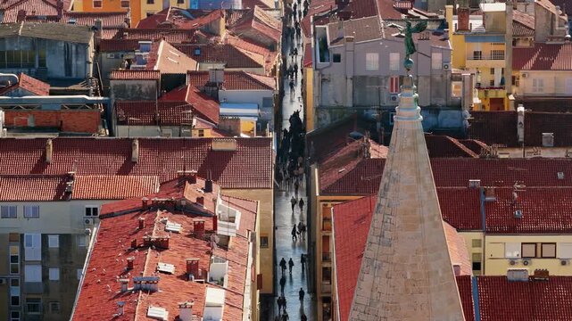 Old town narrow street view with historic architecture and crowd of people walking on cobblestones.