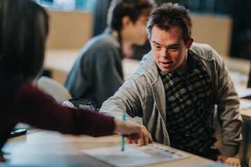 Young male student getting one-on-one help from a teacher at a desk. A teacher points to a...