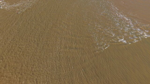 Aerial view of the meeting point of land and water, where the shoreline is lined with cars and a protective barrier, Felixstowe, Felixstowe, United Kingdom.