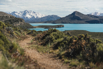 Obraz premium Hiking trail overlooking turquoise lake and snowy mountains