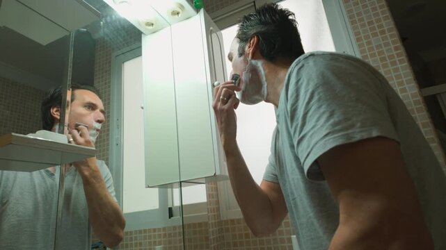 Man Shaving Face in Bathroom Mirror as Part of His Daily Grooming Routine