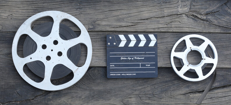 movie clapperboard and film strip on a wooden background