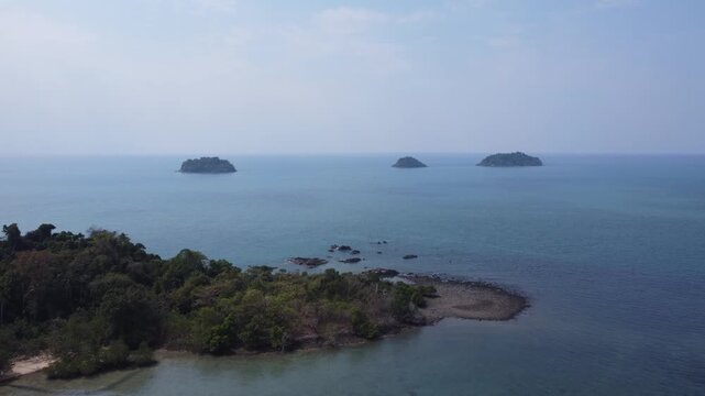 High-quality drone footage circling Ko Man Nai island near Koh Chang. White sandy beaches meet emerald jungle and vibrant turquoise sea, offering a breathtaking tropical landscape perfect for travel.