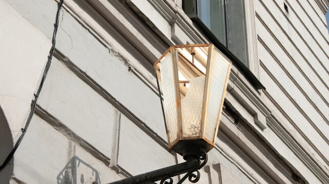 Vintage street lamp on a classic historic building facade with decorative stucco and a metal drainpipe in Kyiv, Ukraine.